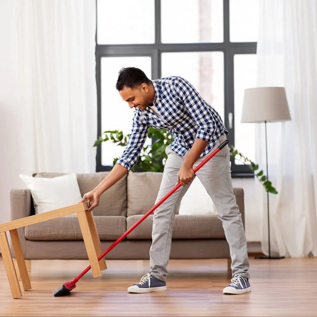 Man swiping the floor with a red broom 
